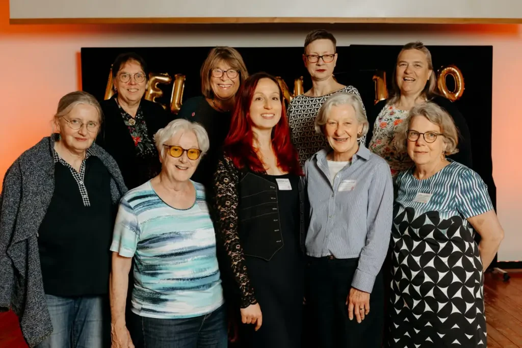 Frauen posieren gemeinsam vor schwarzer Festdekoration