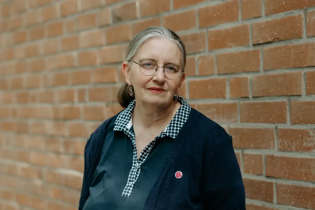 Porträt einer Frau mit Brille vor einer Backsteinwand