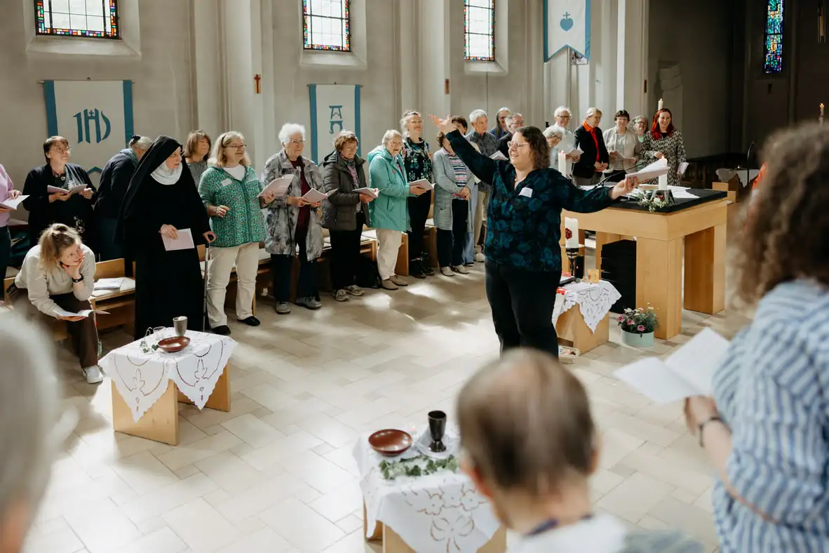 Chor singt mit Dirigentin in einer Kirche