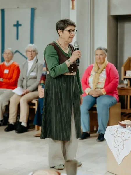 Frau spricht mit Mikrofon in einem Kirchenraum